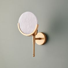 a round mirror mounted to the side of a wall next to a gold faucet