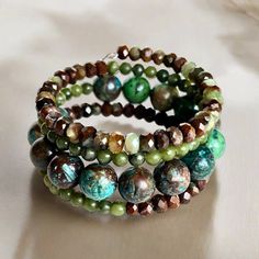 Shades of green, blue, and brown dominate this beaded coil wrap bracelet. Faceted chrysoprase, round jade, and African turquoise come together in a medley of tone and texture in this done-for-you stack. I love the earth tones and contrast of size, color, and texture in this one-of-a-kind bracelet. 4mm round jade 4x5mm faceted chrysoprase 10mm African turqouise one size fits most - best for small to medium wrists Handmade in Lincoln, Nebraska Artisan Turquoise Hand Wrapped Wrap Bracelet, Artisan Hand Wrapped Turquoise Wrap Bracelet, Artisan Hand Wrapped Wrap Bracelet With Round Beads, Green Bohemian Jewelry For Healing, Green Gemstone Beads Bohemian Wrap Bracelet, Bohemian Agate Beaded Bracelets, Bohemian Wrap Bracelet With Faceted Round Beads, Handmade Wrap Bracelet With Round Beads For Healing, Green Bohemian Wrap Bracelet With Gemstone Beads