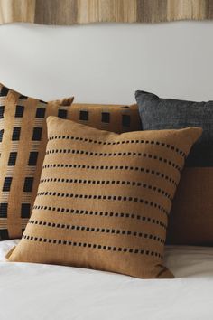 three pillows on top of a bed with white sheets and black polka dot design in the middle