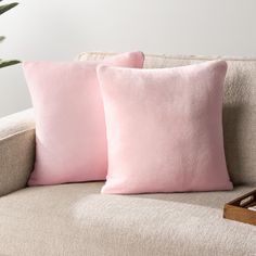 two pink pillows sitting on top of a couch