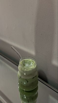 a green drink sitting on top of a window sill next to a white wall