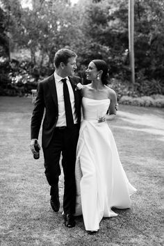 black and white photo of bride and groom walking in the grass together at their wedding