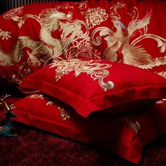 two red pillows with gold dragon designs on them sitting on the floor next to each other