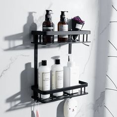 two black shelves with bottles and soaps on them in a white bathroom wall next to a towel rack