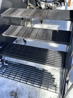 three metal shelves sitting next to each other in the middle of snow covered ground with bicycles parked behind them