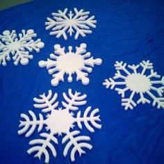 five snowflakes sitting on top of a blue tablecloth covered in white frosting