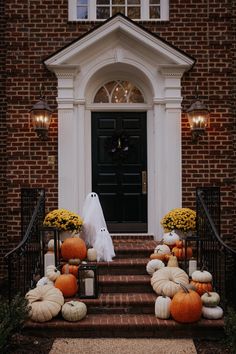 pumpkins and gourds decorate the front steps of a brick house for halloween