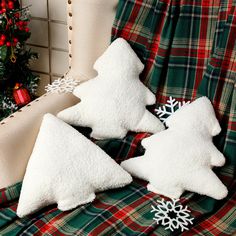 three snow - covered christmas trees sitting on top of a blanket next to a christmas tree