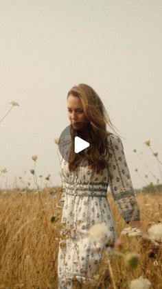 a woman walking through a field with tall grass