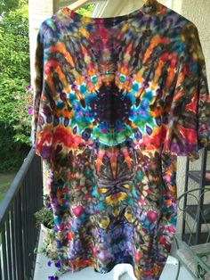 a colorful tie - dyed shirt is hanging on a porch