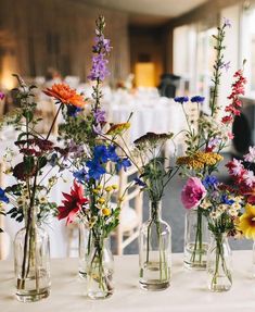 several vases filled with colorful flowers on top of a white tablecloth covered table