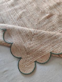 a close up of a blanket on top of a bed with green trimmings