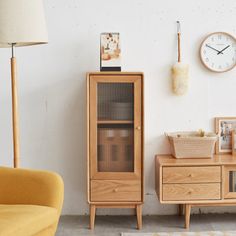 a wooden cabinet sitting next to a yellow chair in a room with a clock on the wall