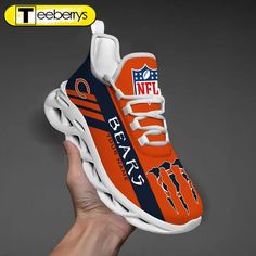 a hand holding an orange and blue sneaker with the nfl logo on it's side