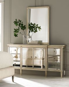 a mirror sitting on top of a dresser next to a white couch in a room