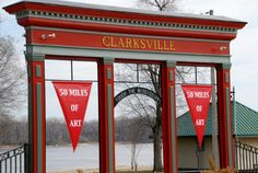 the entrance to clarksville is decorated with red and white banners that read 50 miles of art