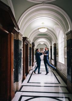 two men in suits walking down a hallway