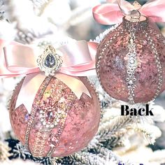 two pink christmas ornaments with bows on them