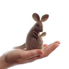 a hand holding a small stuffed animal in it's palm, against a white background