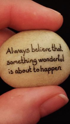 someone is holding a rock that says, always believe that something wonderful is about to happen