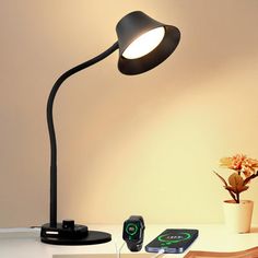 a desk lamp sitting on top of a table next to a phone and remote control