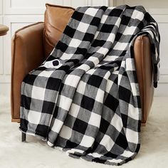 a black and white checkered blanket sitting on top of a brown leather chair next to a table