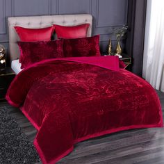 a bed with red comforters and pillows in a room