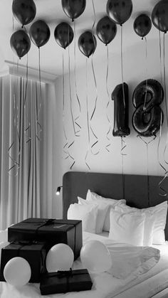 black and white photograph of balloons hanging from the ceiling above a bed in a bedroom