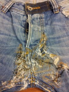 an old pair of jeans that have been ripped and stained with gold paint on them