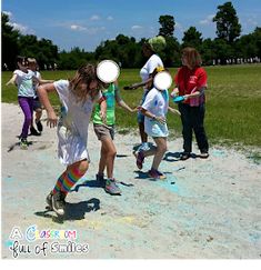 a group of children playing with frisbees in the dirt on a sunny day