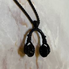 a pair of headphones hanging from a black cord on a marble surface with white background