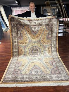 a man is holding up a large rug