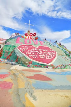 a large heart shaped sign on top of a hill covered in colorful paint and graffiti