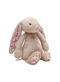 a stuffed rabbit with pink flowers on it's ears and tail, sitting in front of a white background