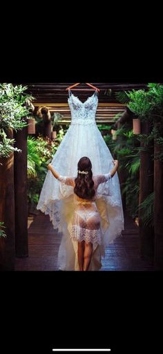 a woman walking down a wooden walkway next to a wedding dress