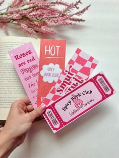 someone is holding up some pink tickets to show off their book club name and logo