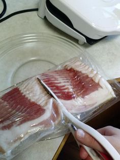 a person cutting meat with a knife on top of the counter next to a food processor