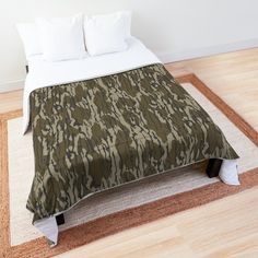 the bed is made up with a green camo comforter on top of it