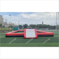 an inflatable bouncer on the grass at a sports field with blue sky and clouds