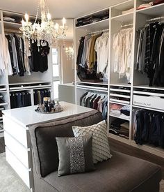 an organized closet with clothes and chandelier