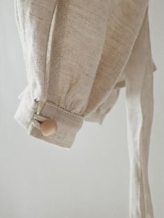 a white curtain with buttons hanging from it's side and some fabric on the back