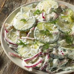 a white plate topped with cucumber and radishes on top of a wooden table