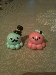 two little toys are sitting on the floor next to each other, one is wearing a top hat