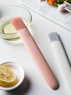 a pink toothbrush sitting on top of a table next to a bowl of lemons