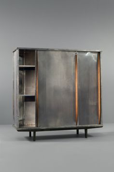 an old metal cabinet with two doors and some shelves on one side, against a gray background