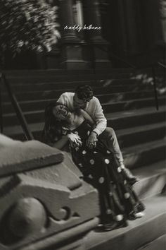 a man and woman kissing on top of a stair case in front of a building