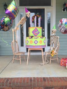 two skeletons sitting on chairs in front of a birthday cake