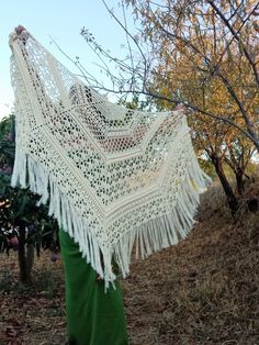 a woman is holding up a crocheted shawl