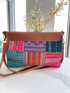 a multicolored purse sitting on top of a table next to a potted plant