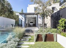 a house with a swimming pool in the front yard and landscaping around it, as well as an outdoor dining area